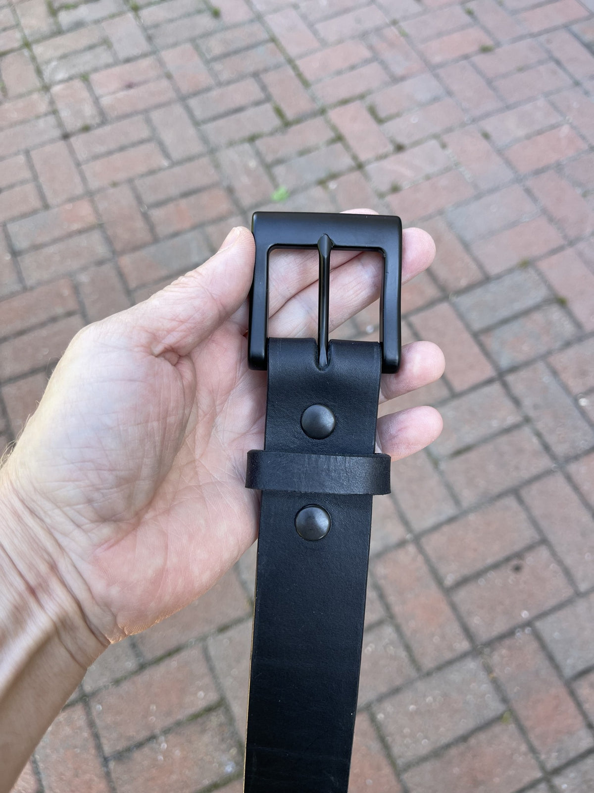Black English Bridle belt with matte black buckle held in hand