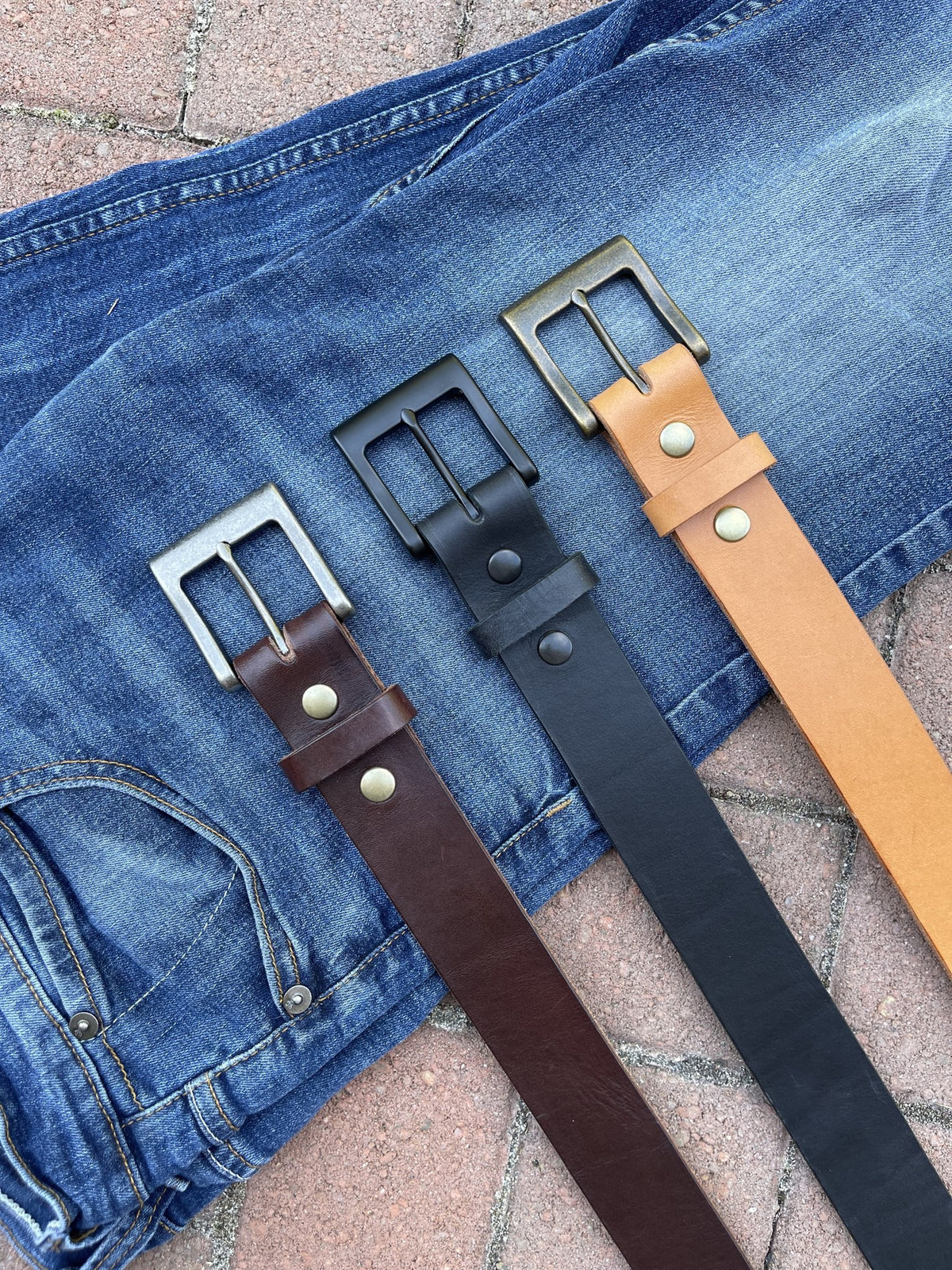 Hermann Oak English Bridle belt collection laid out on jeans